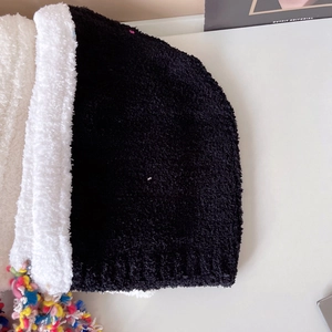 Close-up of plush black and white knit hat with colorful tassels and soft fuzzy texture