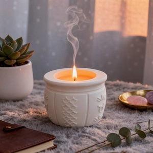 Arabic symbol embossed candle jar with white plaster texture and lit yellow wax