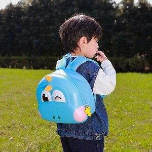 Blue dinosaur hardshell backpack for toddlers shown on a child outdoors in a park