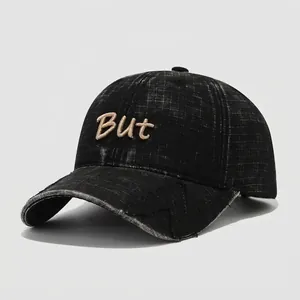 Close-up detail of vintage black cotton kids baseball cap with BUT embroidery and worn edges