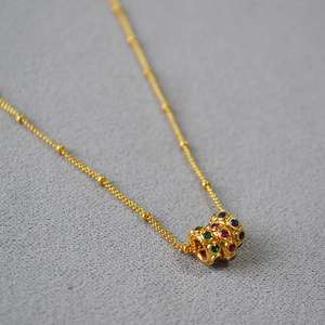 Gros plan du pendentif plaqué or serti de zircons rouges, verts et bleus étincelants
