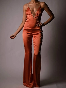 Detailed view of orange satin jumpsuit featuring a deep V-neck and metal chain accessory