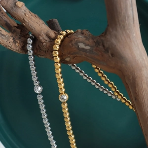 Gold and silver beaded bracelets set with round crystals displayed on a branch