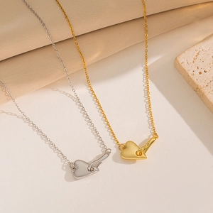 Golden and silver heart key pendant necklaces in titanium steel on stone background