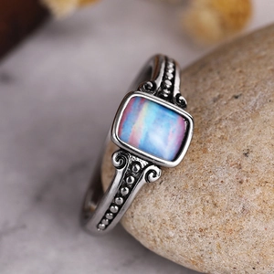 Macro shot of vintage silver ring with square iridescent opal and ornate scroll embossing