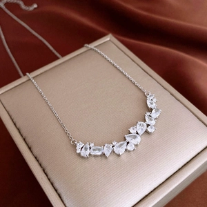 Detail of silver chain necklace with drop-shaped zircon pendant on luxury satin