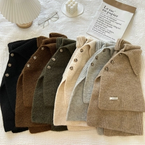 Flat lay of knit scarves with buttons in various colors on a cozy white background