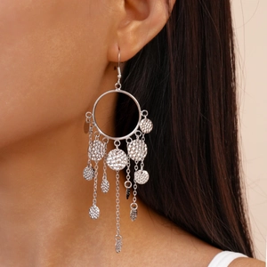 Gros plan détaillé de boucles d'oreilles à pompons argentés avec sequins martelés