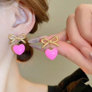 Boucles d'oreilles pendantes cœur en émail rose et nœud doré élégant pour femme