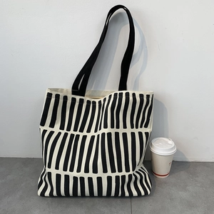 Detail view of large canvas tote bag with black and white stripes and sturdy handles