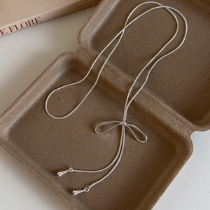 Collana con ciondolo a fiocco argento con catena a serpente e nappine in un portagioie