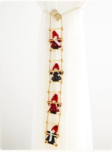 Detail of wool felt Santa dolls on a rope ladder hanging against a white curtain