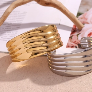 Close-up of golden and silver wide wave-patterned bangles with high-polished mirror finish