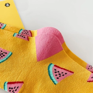 Close-up of yellow cotton socks with pink and green watermelon patterns and logo detail