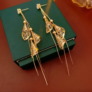 Gros plan de boucles d'oreilles pompons dorées avec pierres carrées et breloques en éventail