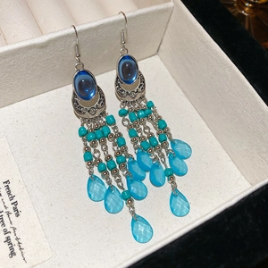 Close-up of Bohemian earrings with blue resin droplets and ornate silver hollow metalwork