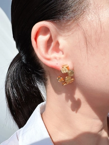 Detail view of retro gold C-shaped earrings with layered relief coin portraits on a model