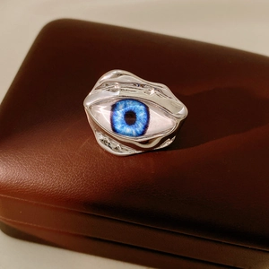 Macro view of blue eyeball ring on leather box showing irregular silver wave texture