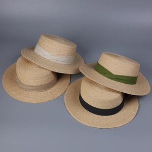 Détail de quatre chapeaux canotiers en raphia avec rubans beige, vert, marron et noir