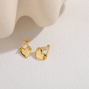 Detail of minimalist gold heart lock drop earring on an aesthetic white textured background