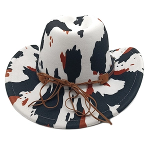 Detailed close-up of cow print cowboy hat with brown leather band on white background