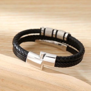 Close-up of black braided leather bracelet with silver magnetic buckle on wood surface