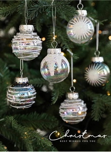 Close-up of clear 6cm iridescent Christmas ball with white glitter stars on a festive tree