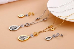 Detail of leaf-shaped titanium steel necklace and earrings with Forever Love engraving