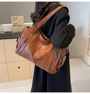 Close-up of brown vintage leather tote bag with dual straps and textured finish on model