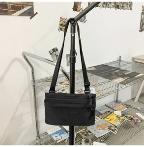 Detail view of durable black nylon crossbody bag with multi-layer zippers and adjustable strap
