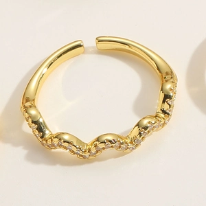 Détail d'une bague ouverte ondulée plaquée or 14K ornée de pierres de zircon brillants