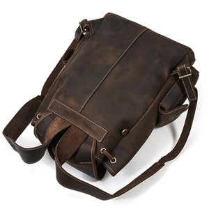 Macro view showing natural leather texture and fine stitching on dark brown backpack