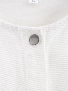 Detail of white denim vest neckline with matte silver metal button and size S tag