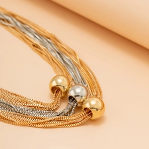 Close-up of layered box chains with gold and silver metallic sphere pendants