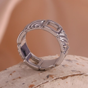 Macro shot of silver textured ring with hollow rectangular patterns on a stone surface