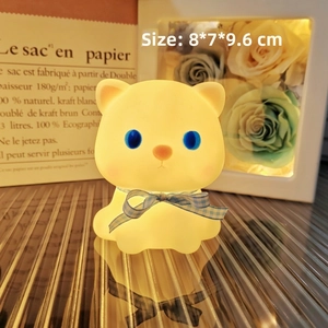 Macro detail of cat night light showing blue bow tie and warm yellow glow finish