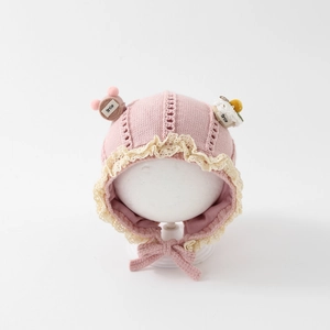 Detailed knit of pink baby bonnet with lace trim, Smile tag and cute cake charm
