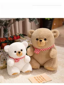 Detail of white and brown plush teddy bears with red checkered scarves in festive setting