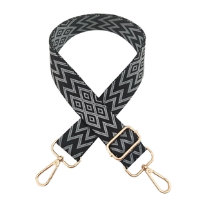 Detail of adjustable woven shoulder strap with black and white diamond pattern and gold hooks