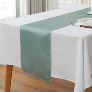 Detail of teal green satin table runner with smooth fabric and hemmed edges for weddings