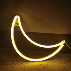 Detail of warm yellow LED moon neon light with hanging hole on a dark wall background