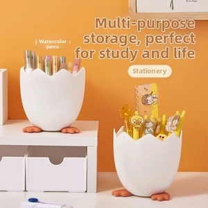 Detail of egg-shell stationery holder with orange feet on a vibrant orange background