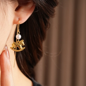 Detail of golden rocking horse earring with pearl on model, s925 silver ear wire