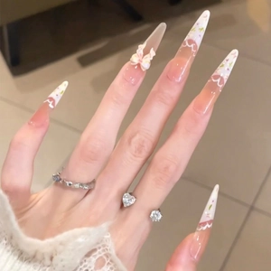 Pink French lace nails with bow accents in long almond shape for a feminine look