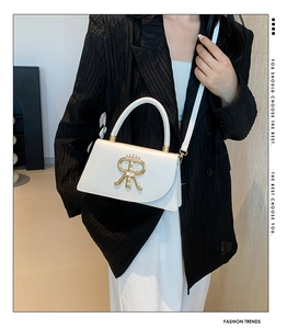 Close-up of white crossbody bag with golden RR logo and leather handle strap detail