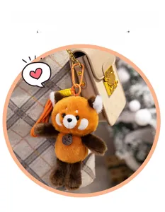 Red panda plush keychain hanging on a beige embossed leather bag with orange clip