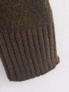 Detail of ribbed cuffs on dark olive green knit sweater with soft wool texture
