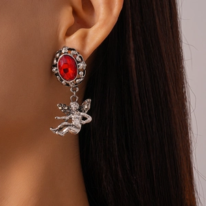 Close-up of vintage silver earrings with red oval gemstones and angel cherub pendants
