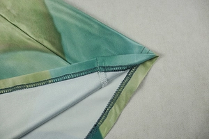 Detailed view of the fine stitching and silky fabric texture on a green gradient dress
