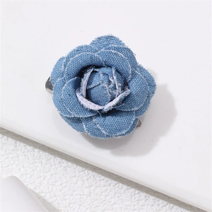 Detailed close-up of blue denim fabric camellia flower brooch with textured petals